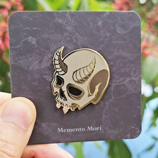 Gold hard enamel pin featuring a horned devil skull