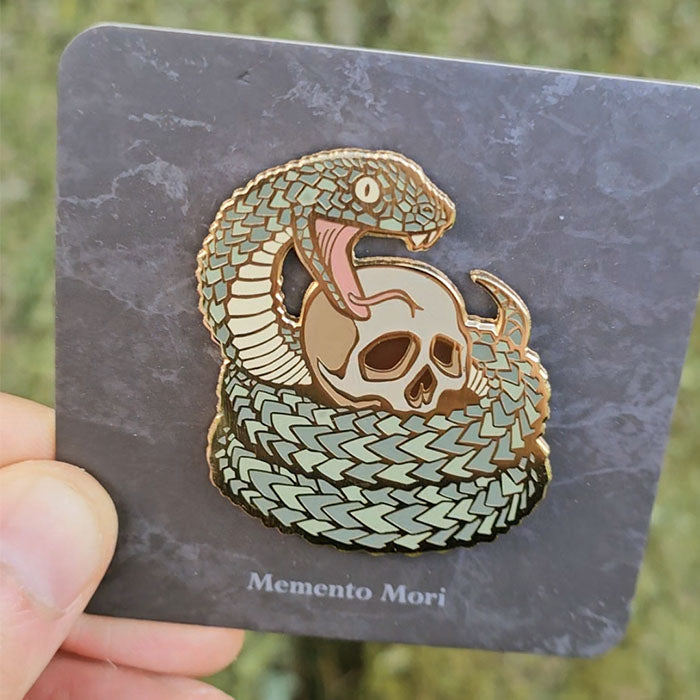 Gold hard enamel pin featuring a viper snake wrapped around a skull
