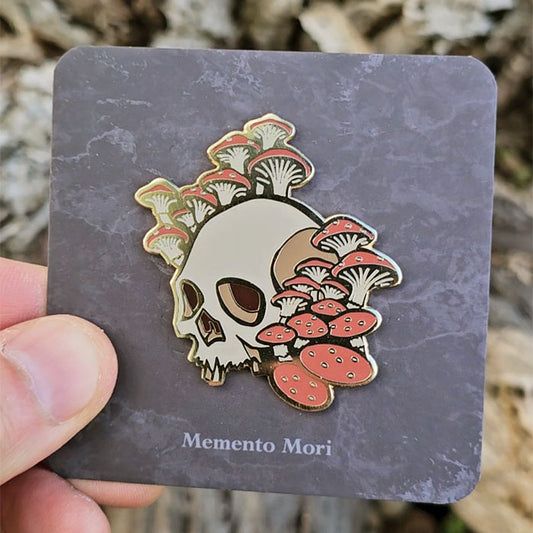 Gold hard enamel pin featuring a skull surrounded by redcap mushrooms