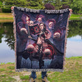 Person holding a large tapestry with a fantasy design featuring a woman and skulls by a lake.
